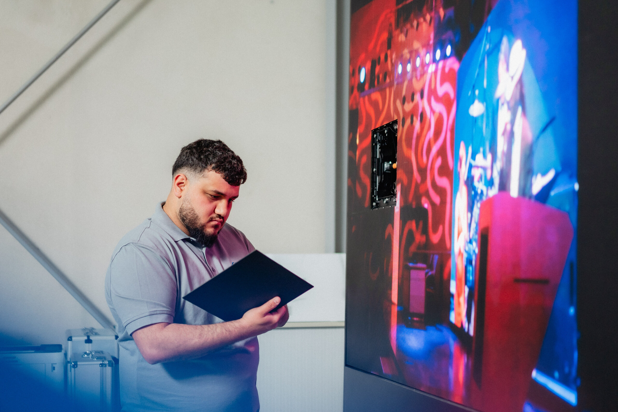 Mitarbeiter überprüft die Funktion einer Videowand im Bereich Digital Signage.